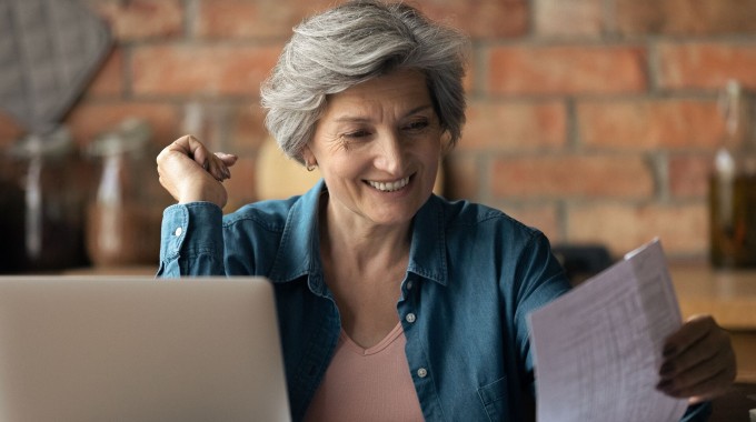 Mujer revisando papeles y en su computador