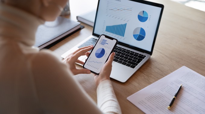 Mujer revisando gráficos en su computador y celular 