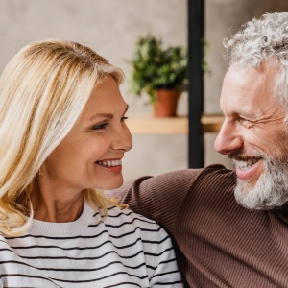 pareja en el living de su casa mirandose mientras sonrien